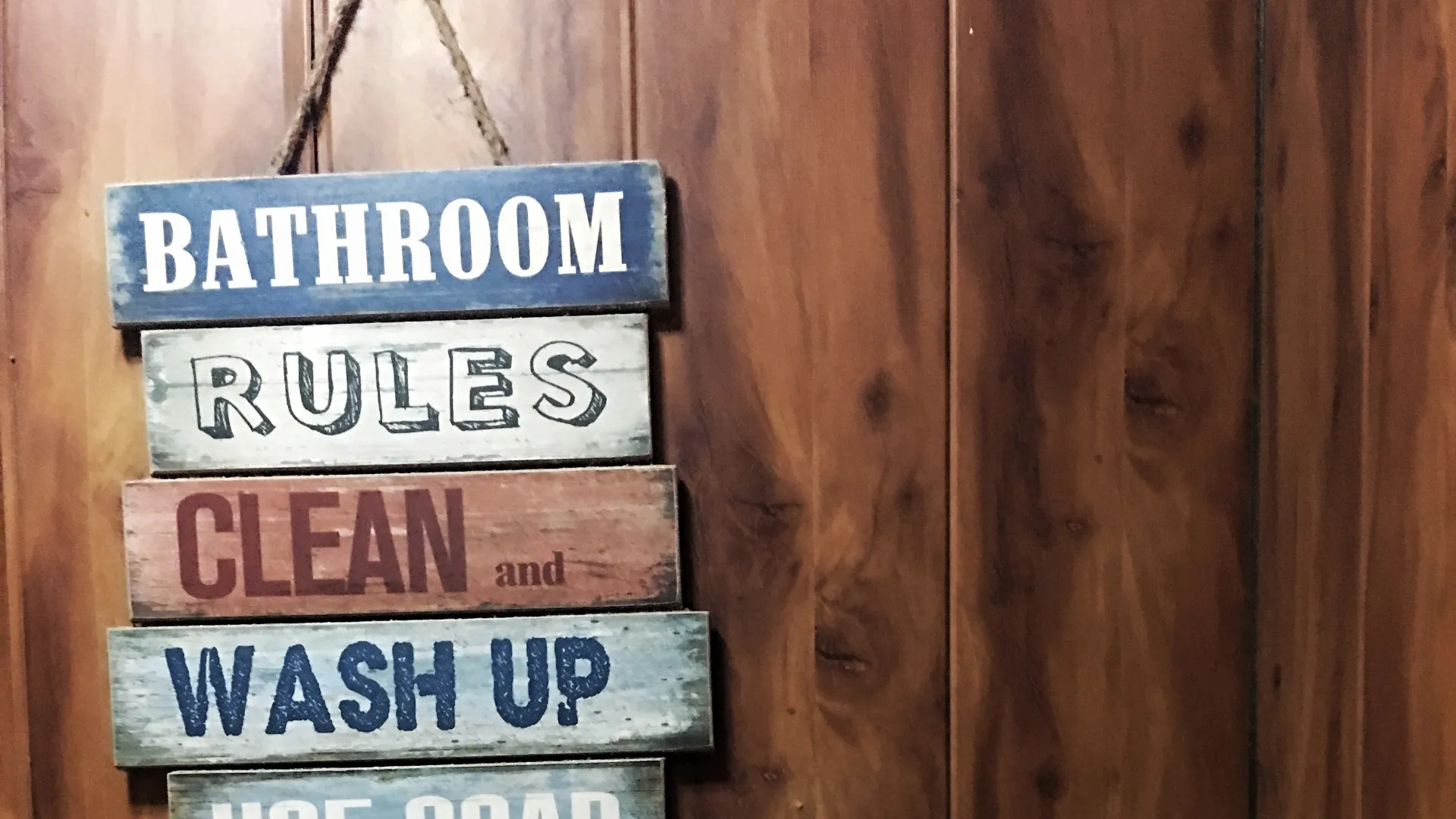Rustic wooden bathroom rules sign on a timber wall.